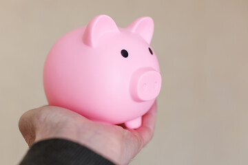 A man holds a pink piggy bank in his palm. The concept of investments and savings. Copy space.