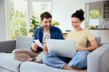 Carefree couple calculating home finances sitting together with laptop on sofa