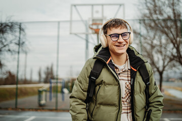 Portrait of a young smiling man wear headphones on basketball court 