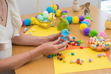 A woman fills plastic Easter eggs with egg-shaped candies. Egg hunt concept. Happy Easter