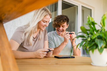 Man and woman watching a game console in a terrace in summer. Technology and game addiction concept