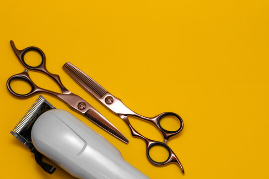 Hairdressing and barber tools. Professional scissors and hairdressing clipper. Bright yellow background.
