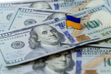 Hundred dollar bills are scattered on the table. National flag of Ukraine on the dollars. Finance of the United States in Ukraine.
