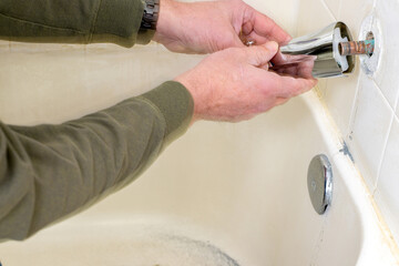 Plumber installs a new bathtub faucet