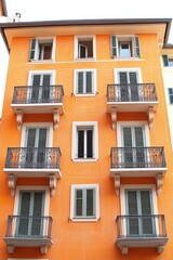 Modern apartment building featuring multiple balconies on the second floor, showcasing contemporary architecture and urban living spaces.