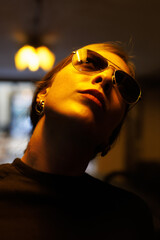 woman smiles confidently with manly sunglasses and stylish earrings at a dimly lit venue in the...