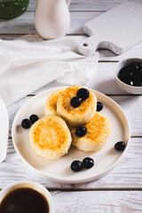 Homemade cottage cheese pancakes and blueberries on a plate on the table vertical view