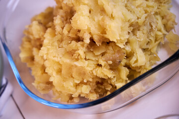 man crushes boiled potatoes for mashed potatoes