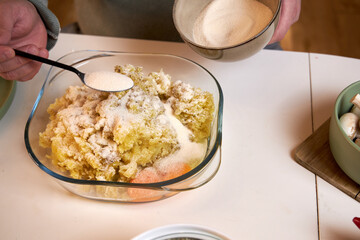 the man puts flour in the potato stuffing