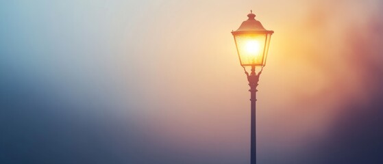 A glowing street lamp stands solitary against a muted twilight background, casting a warm and inviting light amidst evening fog.
