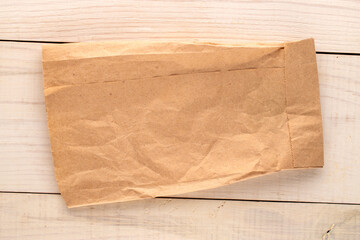 One paper bag on a wooden table, top view, close-up.