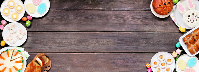 Easter or spring dessert food double border. Overhead view over a dark wood banner background. Bunny cake, colorful cookies, breads, tarts and and a variety of sweets. Copy space.