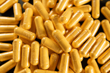 Yellow tablets or pills on the black stone background.