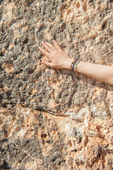 Woman hand with different bracelets on the old stone wall