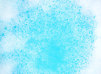 Small foam bubbles in blue water. Abstract white soap foam or soap suds texture. Concept of cleaning and washing.
