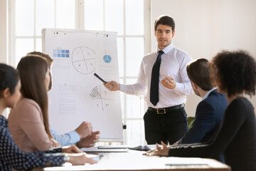 Handsome young businessman, trainer or corporate coach teach audience, standing at front of...