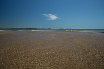 Low tide on a sandy beach in Maine, ripples visible in the shallow water