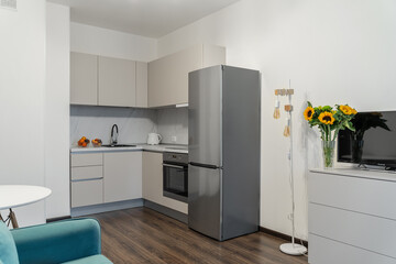 design of built-in modern kitchen in bright colors. beige kitchen cabinets, steel refrigerator, steel faucet. fruits on table. inside home. inside home. Modern built-in kitchen in minimalist style.