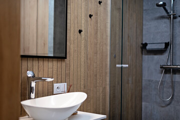Interior of small modern bathroom in brown color and wooden decor. Ceramic washbasin and mirror on the wall. Scandinavian and vitage style.
