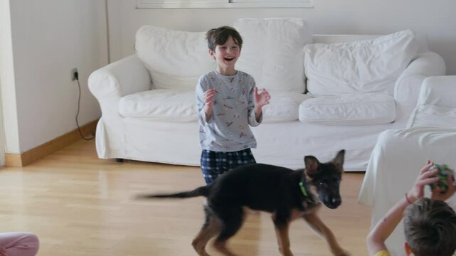 Mother with her kids is happily interacting with a playful dog in a bright living room. The children expresses joy while the dog runs around, creating a warm and lively atmosphere.
