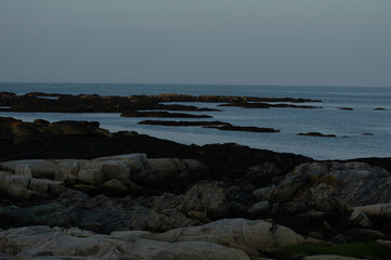 The rocky coastline of Maine featuring blue water and dark rocks
