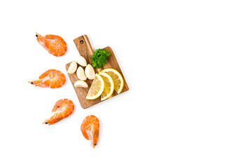 Fresh boiled shrimp, lemon slices, garlic and parsley on a wooden cutting board isolated on a white background.