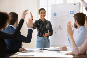 Group of young teammates voting unanimously at meeting in conference room, raise hands, celebrate...