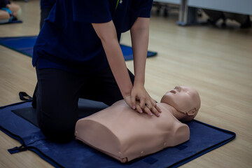 Close-up of Asian hands practicing cardiopulmonary resuscitation (CPR) on a training dummy. Important techniques include chest compressions and maintaining an airway.