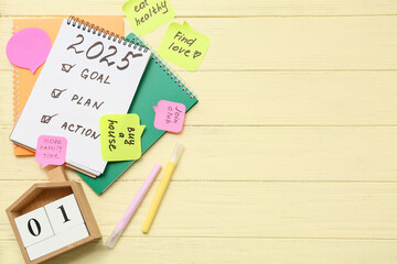 Notebook with to do list, calendar and sticky notes on yellow wooden background. New year goals...