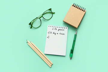 Notebooks with to do list, eyeglasses and stationery on cyan background. New year goals concept