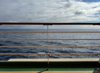 View of a calm sea through railing on the deck of a cruise ship