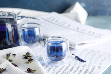 Cup of butterfly pea flower tea on newspaper
