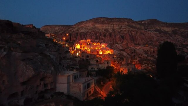 Aerial view of Cavusin village with lights from ruins on rocky hills in Cappadocia region, Turkey