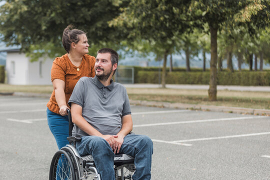 Smiling man, a wheelchair user, and his female assistant enjoying outdoor activity. Disability support concept.