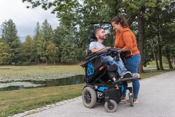 Man, an electric wheelchair user in the warm embrace of his wife, a couple enjoying and showing their affection. Disability and love concept.