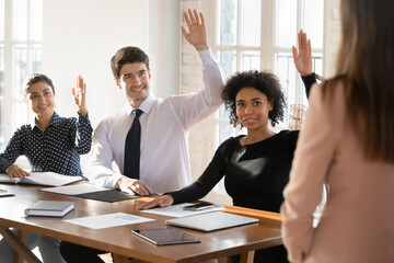 Multinational staff members participate at seminar, training session raising their hands to express...