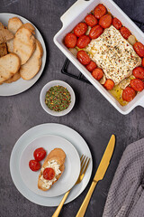 Food photography of roasted feta cheese, tomatoes and garlic with toasted bread, thyme, herbs, healthy  food, Mediterranean cuisine