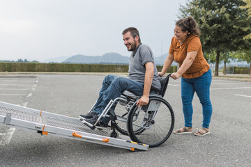 Female assistant helping a male person in wheelchair with transport using accessible vehicle van...