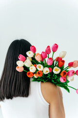 Naklejka premium girl with a bouquet of tulips in her hands on a light background. tulips given to a girl on March 8
