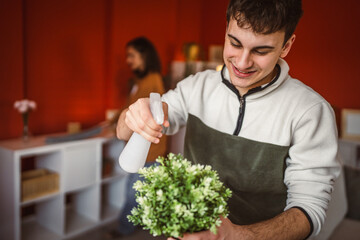 young man gardener use spray for hydration home plant