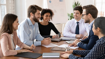 Group of businesspeople engaged in business meeting at conference table, actively discussing joint project, planning cooperation, brainstorming or strategizing. Teamwork, professional communication