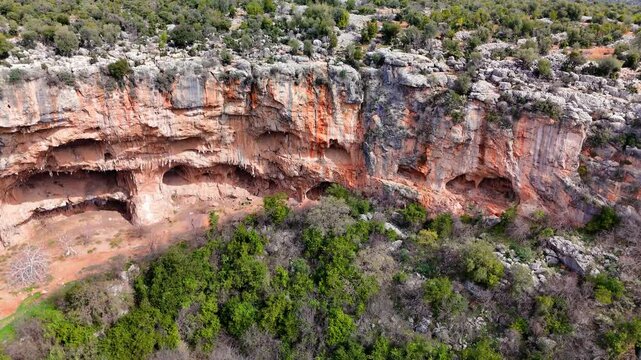Lush vegetation surrounds the red rocky formations of cennet and cehennem sinkholes in mersin, turkey, a popular destination for tourists and nature lovers