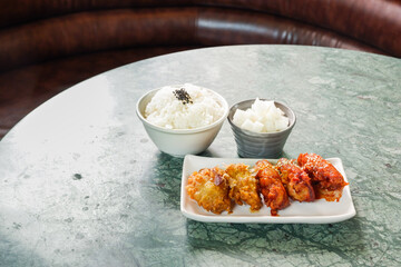 Crispy and Spicy Korean fried chickenon white plate with pickled radish,rice on marble table,Traditional Korean food,Korean foods served on a dining table,The street food of Korea.