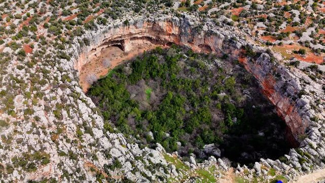 Verdant growth covering rocky depths of cennet and cehennem sinkholes, dramatic landscape formations nestled within taurus mountains, mersin, turkey