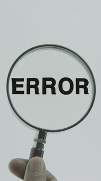 "Error" text or word highlighted by a magnifying glass held by a hand on a white background, symbolizing focus, analysis, and evaluation of mistakes, faults, and system inaccuracies