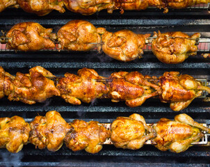 Tasty chickens cooking on grill skews at the market place