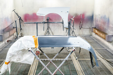 Car parts undergoing preparation for painting in an auto body shop. Sanded bumper and fender set up...