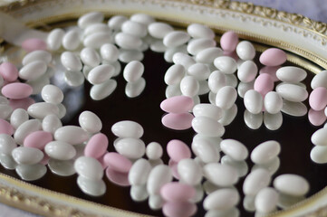close up of white and pink almond candies on glass tray