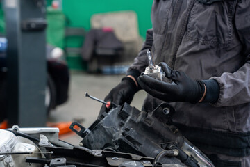 Serviceman repair headlight in car service