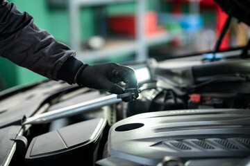 Serviceman checks the oil level in a car engine